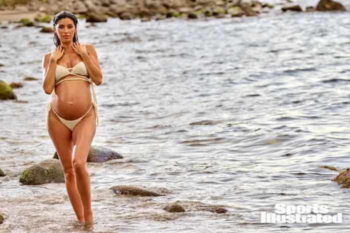 Nicole Williams English stands in the water in a knit strappy bikini top and string bottoms.